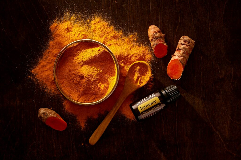 Kurkuma-Pulver mit Holzloeffel auf Stein als Symbol fuer Curcumin