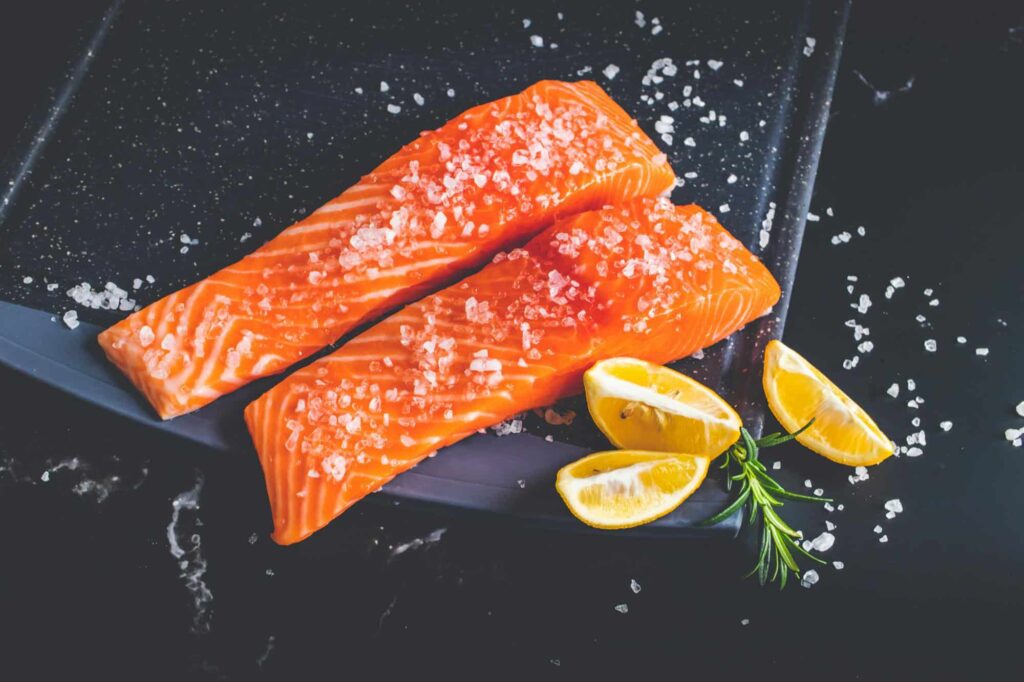 Rohe Lachsfilets mit Salz und Zitrone als Symbol für Omega-3-reiche Ernährung