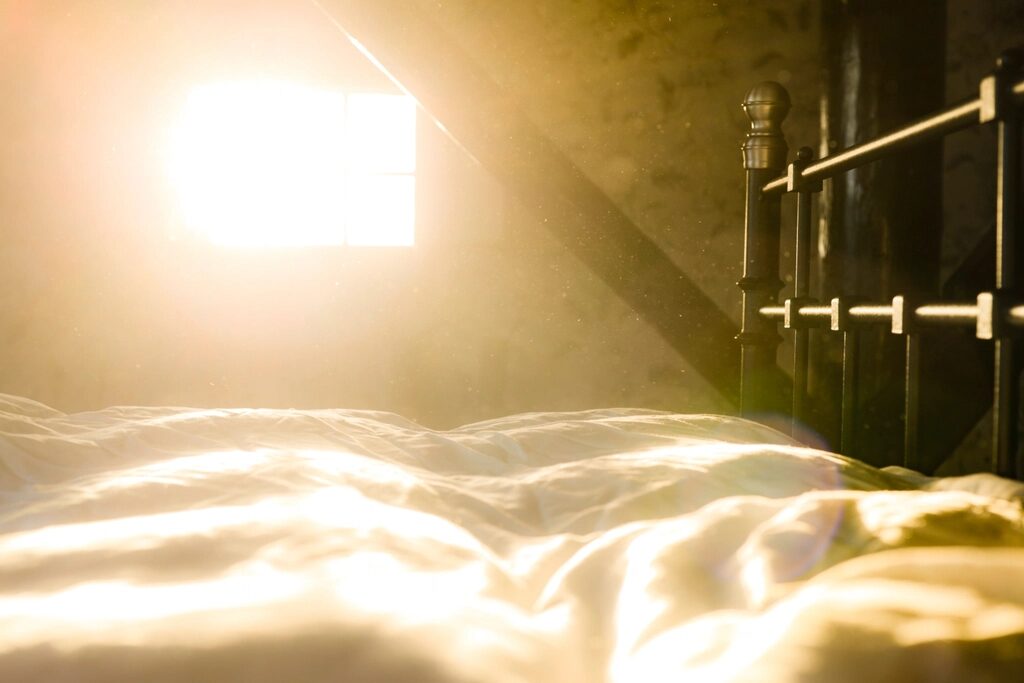 Bett im warmen Morgenlicht – Tageslicht steuert den Schlafrhythmus